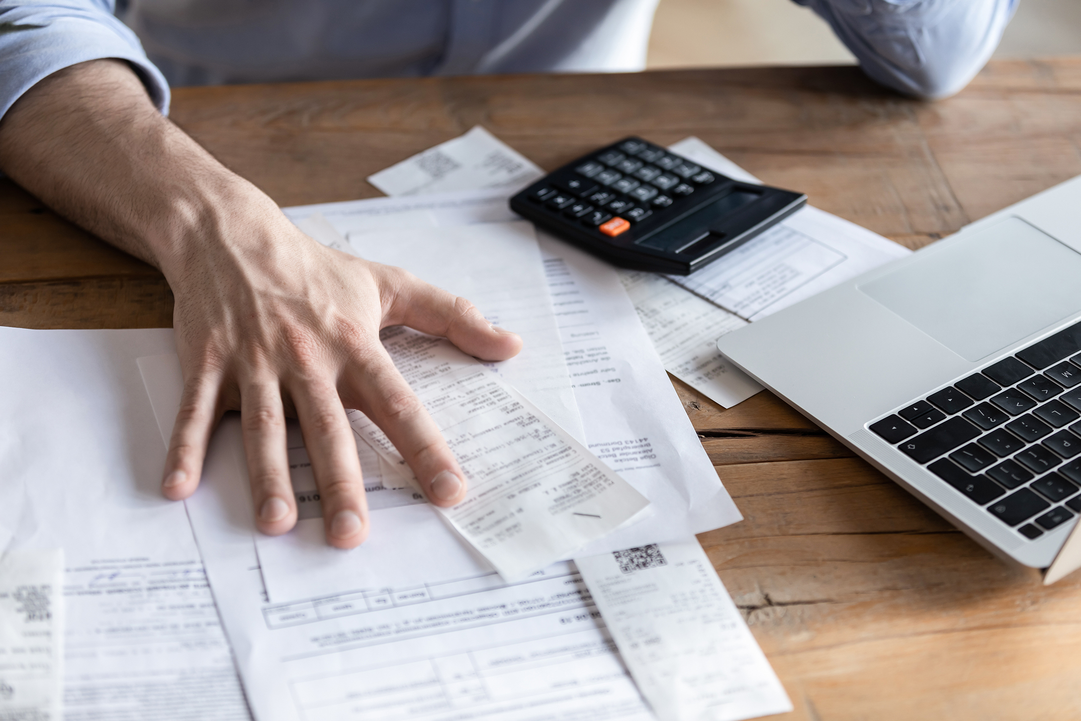 Individual entrepreneur make analysis of firm expenses, accountant do paperwork concept. On desk lot of receipts, calculator and laptop close up view. Man sit at table reviewing bills, managing budget