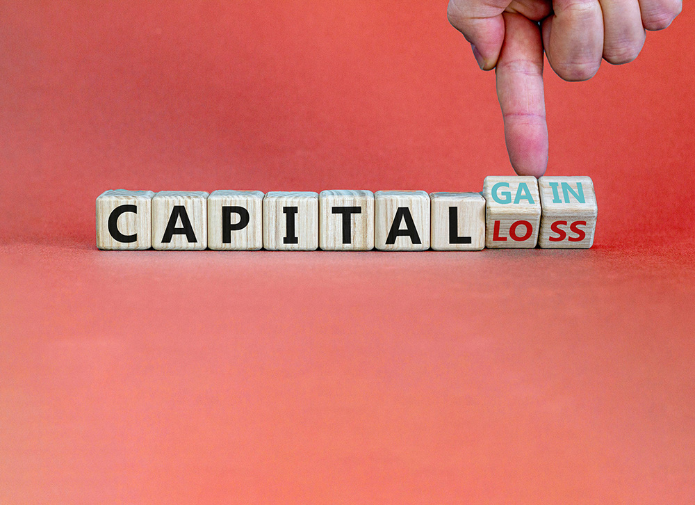 Capital loss or gain symbol. Male hand turns cubes and changes words capital loss to capital gain. Beautiful grey background. Business and capital loss or gain concept. Copy space.