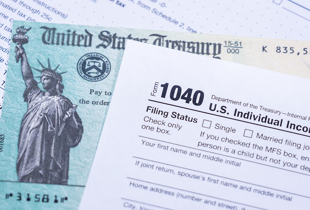 US Treasury stimulus check laying on a form 1040 tax return for 2020 to illustrate questions about qualification for payment