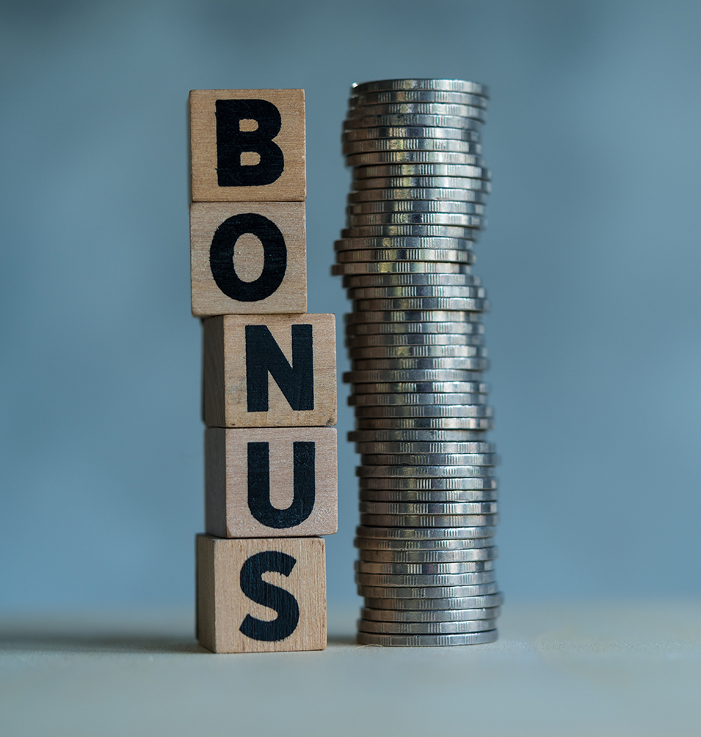 Stacked vertically wooden cubes with letters in the word BONUS and tower created from coins. Receive bonuses, rewards and preferences. Getting benefits and extra points. Benefit, cashback concept