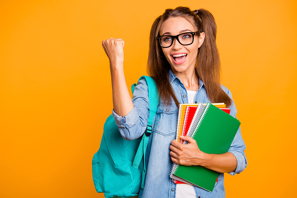 Portrait of her she nice lovely attractive cheerful cheery positive school girl hugging holding colorful copy-book winning gesture fist isolated over bright vivid shine yellow background