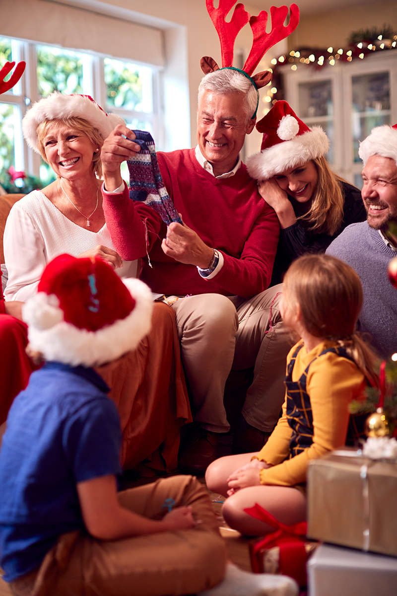 Multi-Generation Family Exchanging And Opening Gifts Around Christmas Tree At Home