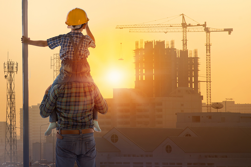 Asian boy on fathers shoulders with background of new high buildings and silhouette construction cranes of evening sunset, father and son concept