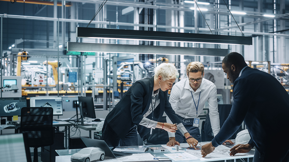 Young Diverse Team of Automotive Engineers Working in Office at Car Factory. Industrial Designer Talks About Electric Engine Parts with Colleagues, Discussing Different Technological Applications.