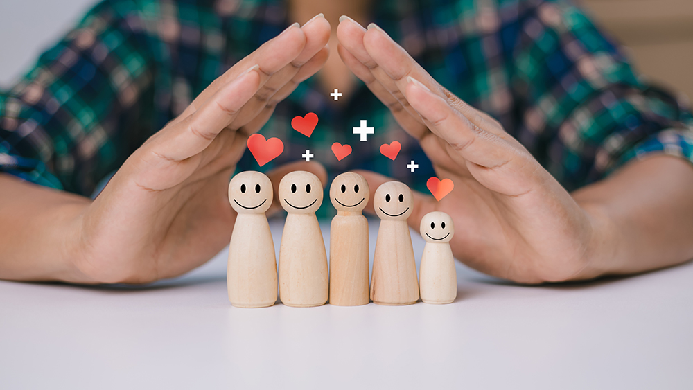 Human hands are choosing life insurance and investing to reduce risk, Wooden dolls with a plus sign and red heart represents protection, Health care planning, Concept of insurance and protection.