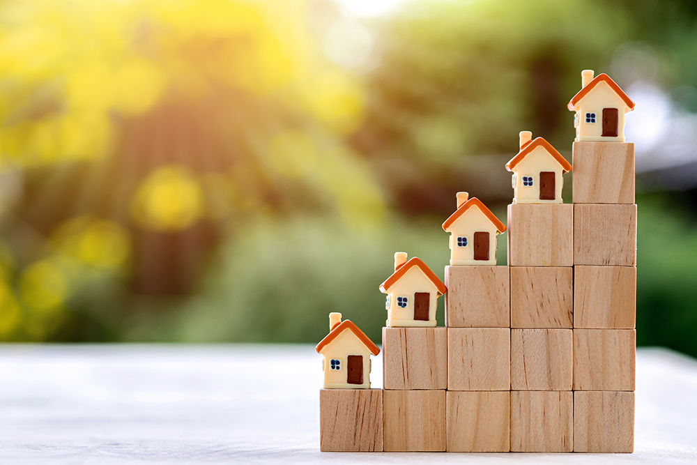 House model placed on top of the growth direction coin. Investing in real estate business for profit or a loan for a home purchase concept.