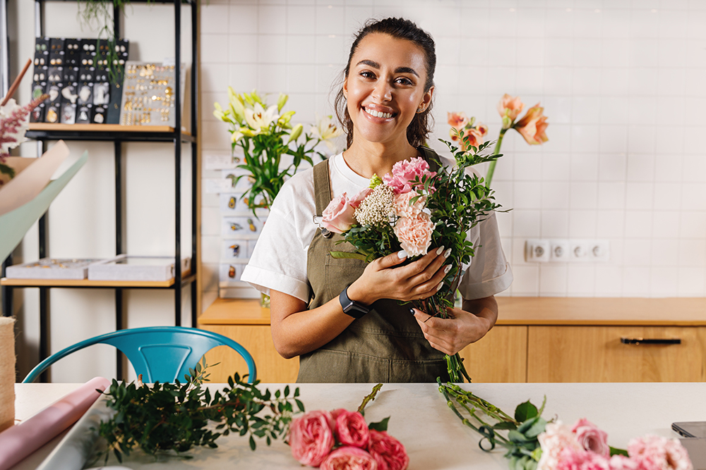 Smiling florist woman holding a bouquet and looking at camera