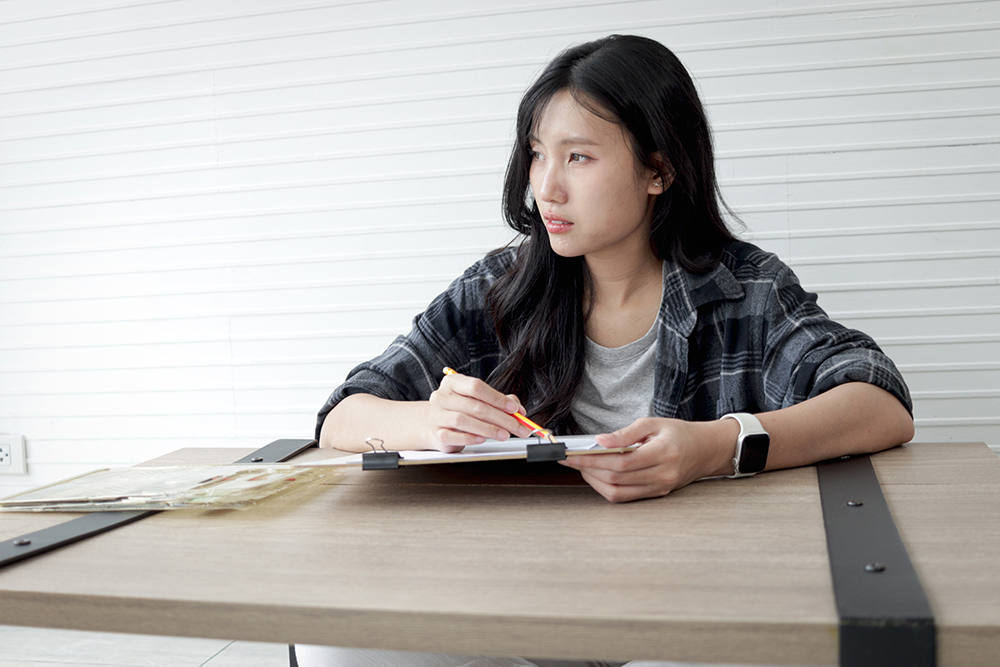 Asian female high school art student taking a break while holding pencil to drawing. Happy woman engages in study art at university. College pupil learning and practice drawing. Senior education.