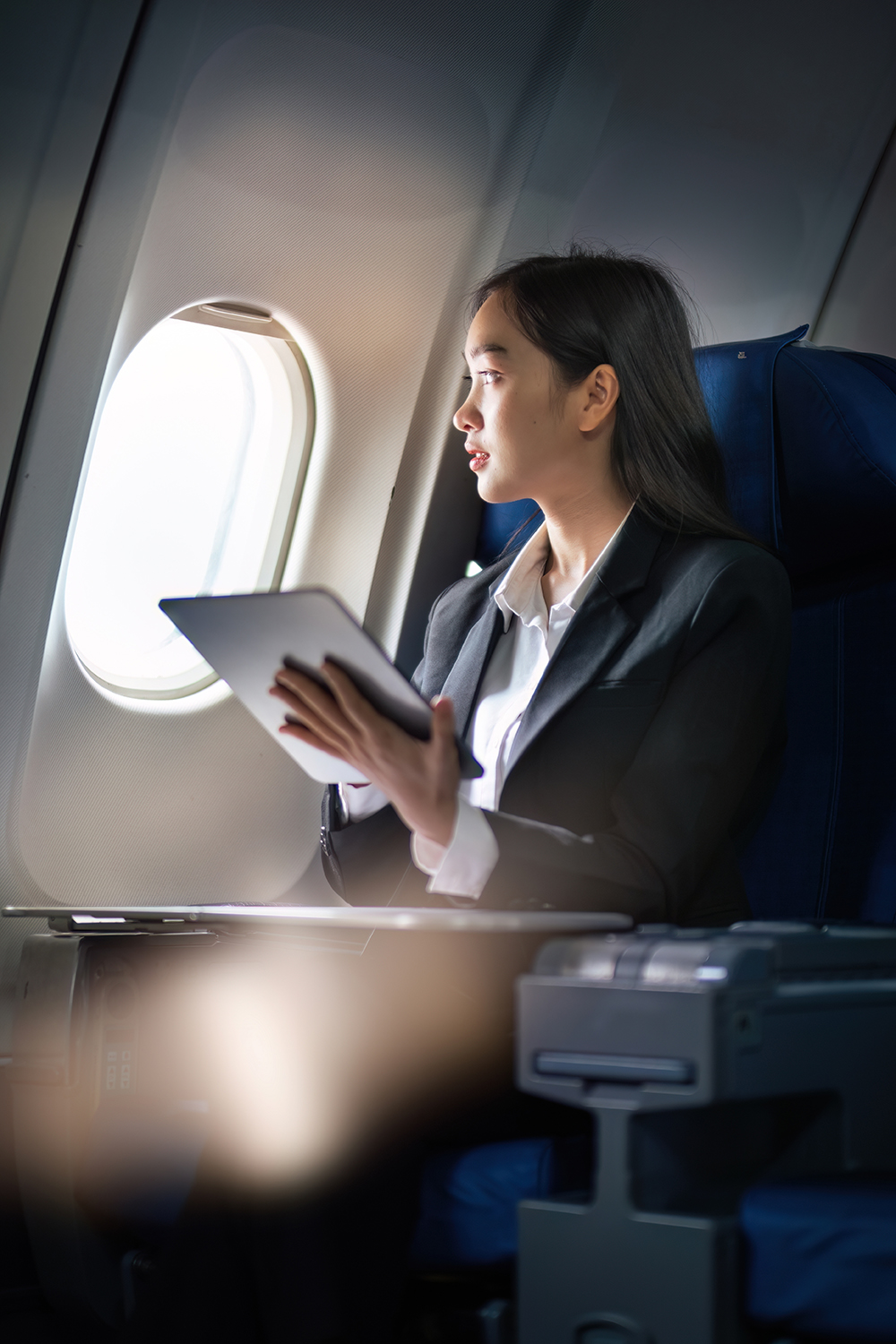 Successful Asian business woman, Business woman working in airplane cabin during flight on tablet