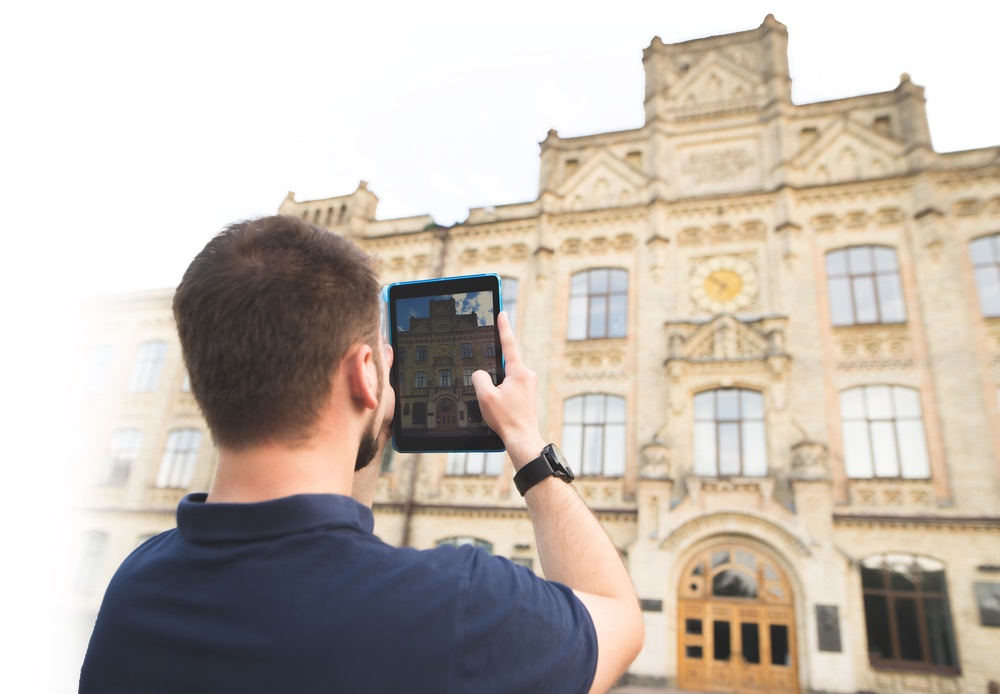 Man makes a picture of the old beautiful architecture on a tablet. Man photographs the building on the tablet