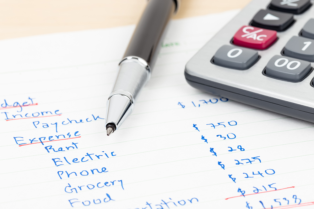 Hand writing home budget with calculator