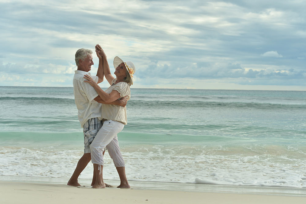 Happy elderly  couple  dancing  on  tropical beach