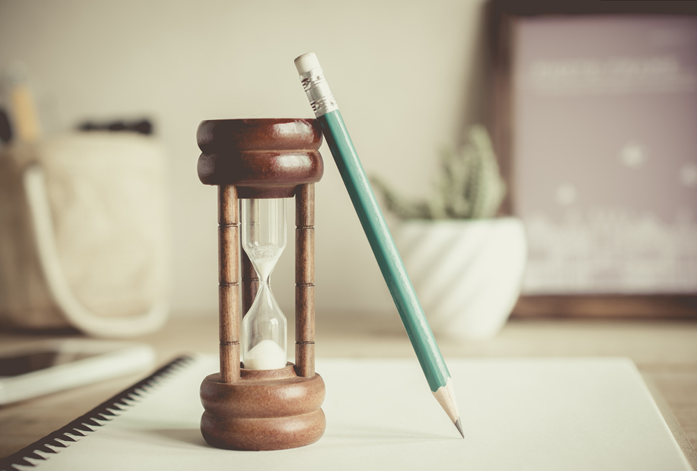 hourglass with pencil on notebook , time passing concept .