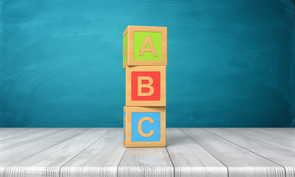 3d rendering of a three toy blocks standing on a wooden desk in one tower with letters A, B and C on them. Primary school. Basic skills. Reading and writing.