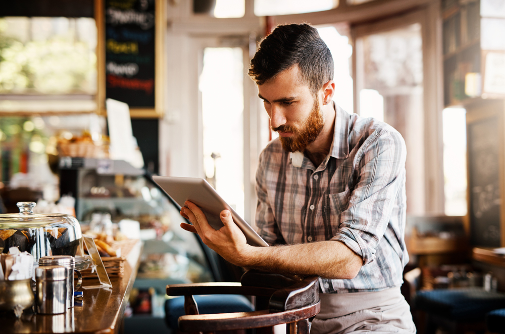 Barista, man and tablet for coffee shop inventory or online order on website in startup cafe. Small business owner, waiter and review with technology for stock menu or price checklist in store