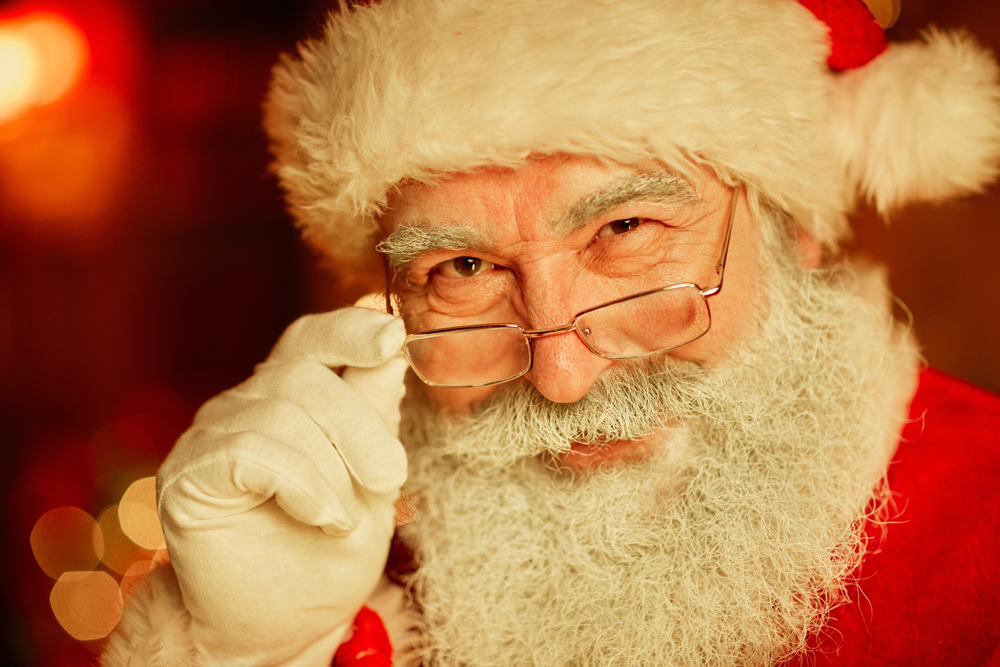 Close up portrait of smiling Santa Claus looking at camera and adjusting glasses on Christmas
