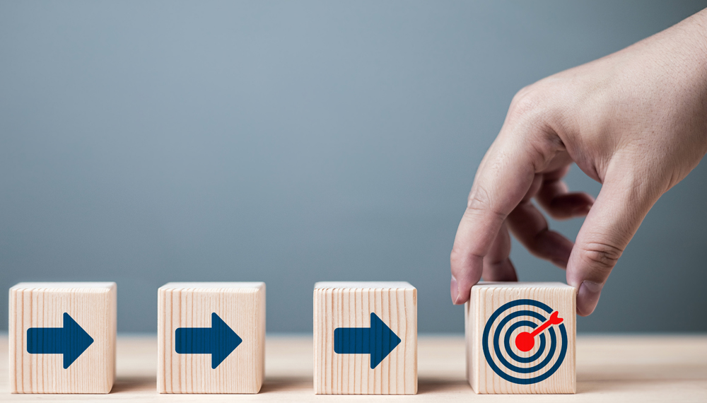 Businessmans hand holds a red dartboard symbol with an arrow pointing at target icon. concept of business defining mission, goals, and processes for success.