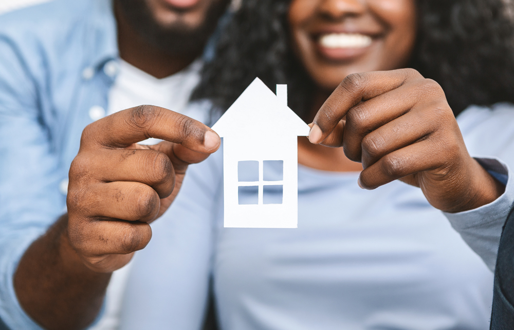 Real estate, housing and family concept. Close up of black couple holding wooden house