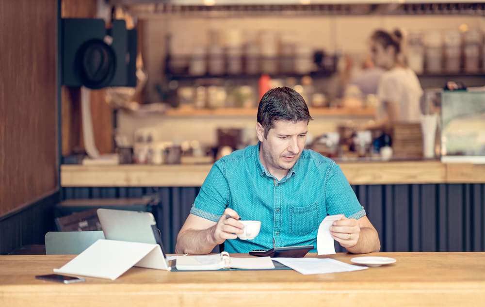 Young man looking over the Restaurant Expenses - Start-up owner going over paperwork of his small business