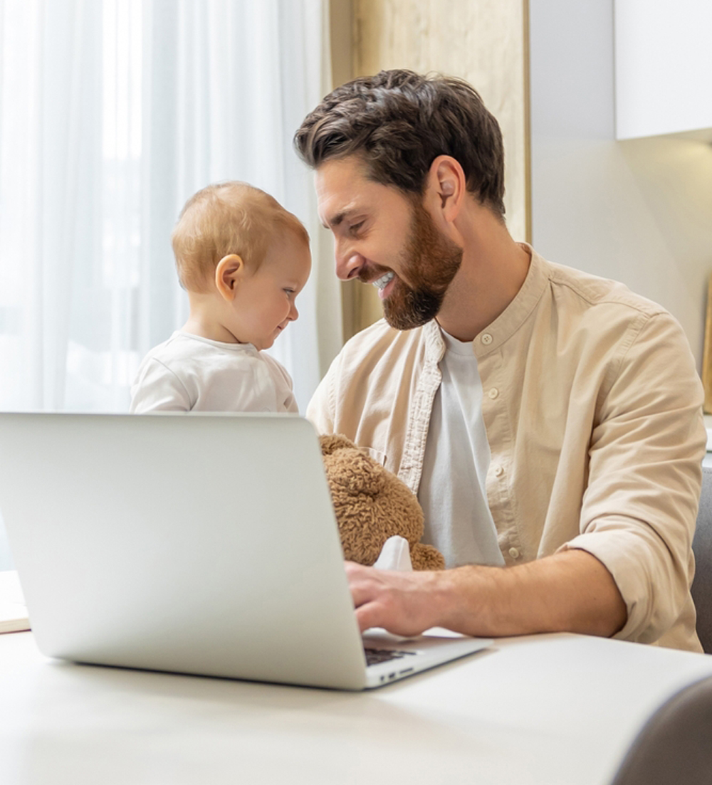 Bearded young caucasian man working from home while taking care of his little son