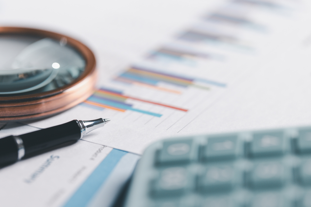 Auditor reviews financial statement and balance sheet on desk using a calculator, representing the concept of accounting, audit, and finance in preparing a detailed financial report for the business.