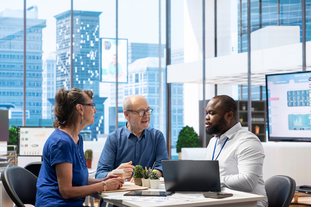 Senior people consulting financial advisor about retirement and pension planning, securing the future with life insurance and savings. Reviewing their financial options in modern office.
