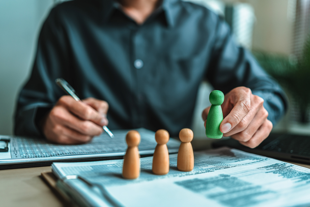 Human Resource is finger choose The wooden doll represents the employee of the company line up on business document and them represents new employee, search job, job career. Corporation concept.
