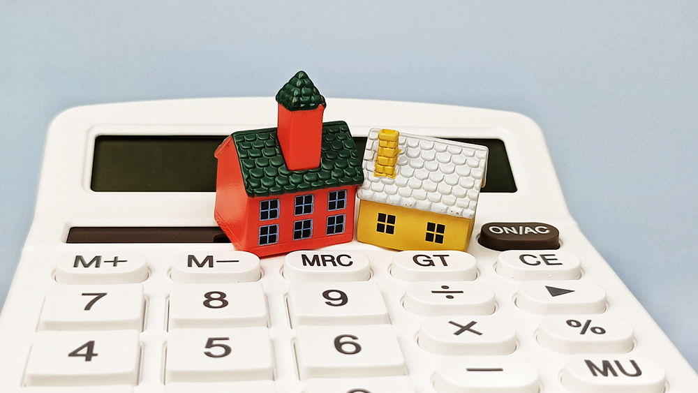 Real Estate Investment Concept with Miniature Houses on Calculator for Mortgage Property Value and Home Finance Cost Calculation. 
