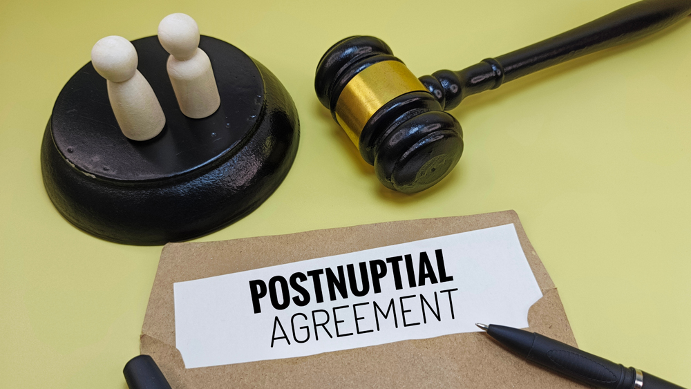 Postnuptial Agreement on Brown Envelope with Judge’s Gavel and Wooden Couple Representing Marriage Contract, Asset Protection, or Legal Relationship Terms. 