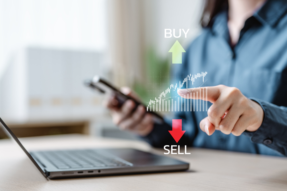 Stock invest trade graph. Invest economy chart financial. Finance analysis. A woman is using her phone to buy and sell stocks. She is pointing at the sell button on her phone.