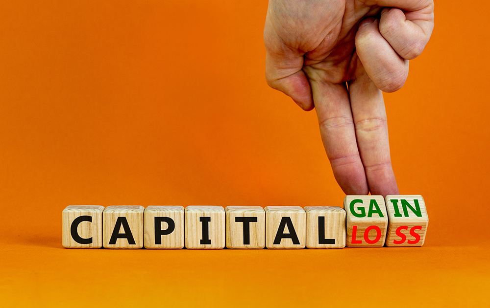 Capital loss or gain symbol. Businessman turns cubes and changes words capital loss to capital gain. Beautiful orange background. Business and capital loss or gain concept. Copy space.