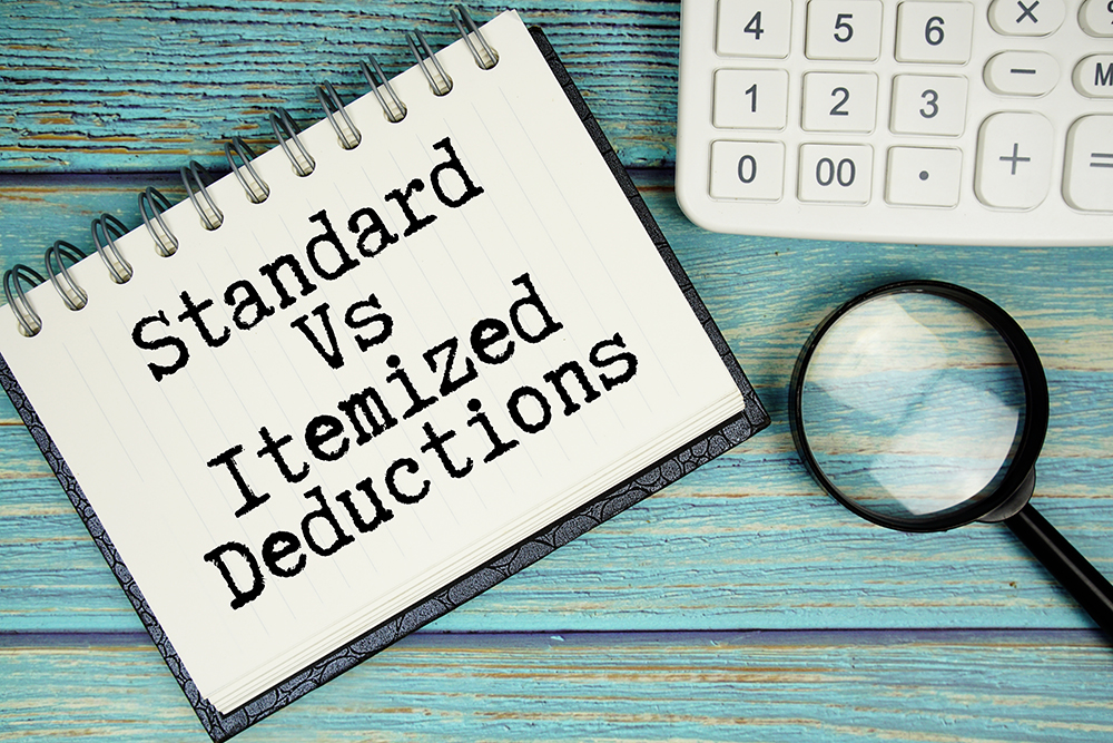 Standard Vs Itemized Deductions text on notepad with magnifying glass and calculator on wooden background