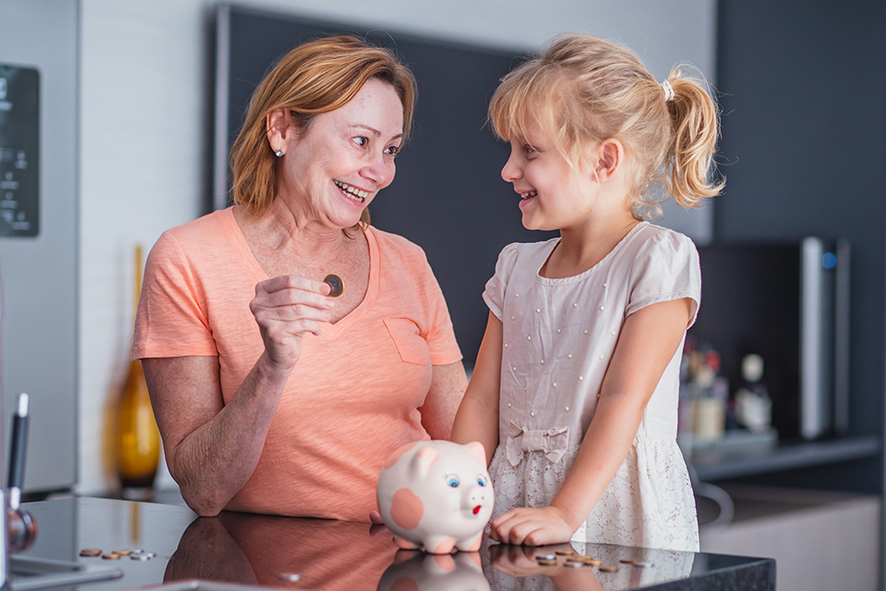 Close up happy older mother and adorable little daughter holding touching pink piggy bank, caring mum and adorable girl child saving money for future, family insurance and investment concept